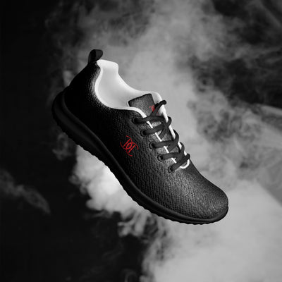 Black athletic sneaker with textured finish, red Cachy’s Urban logo, and white inner lining, showcased on a fiery orange smoke background