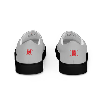 Grey slip-on sneakers with black soles, featuring bold red Cachy’s Urban logo on the front and branded insoles