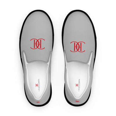 Grey slip-on sneakers with black soles, featuring bold red Cachy’s Urban logo on the front and branded insoles