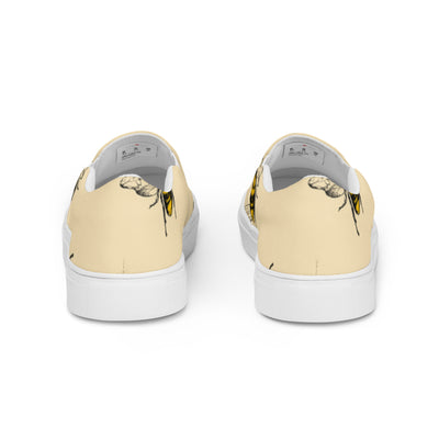 Beige slip-on canvas shoes with a bold bee pattern design and Cachy’s Urban branded insoles