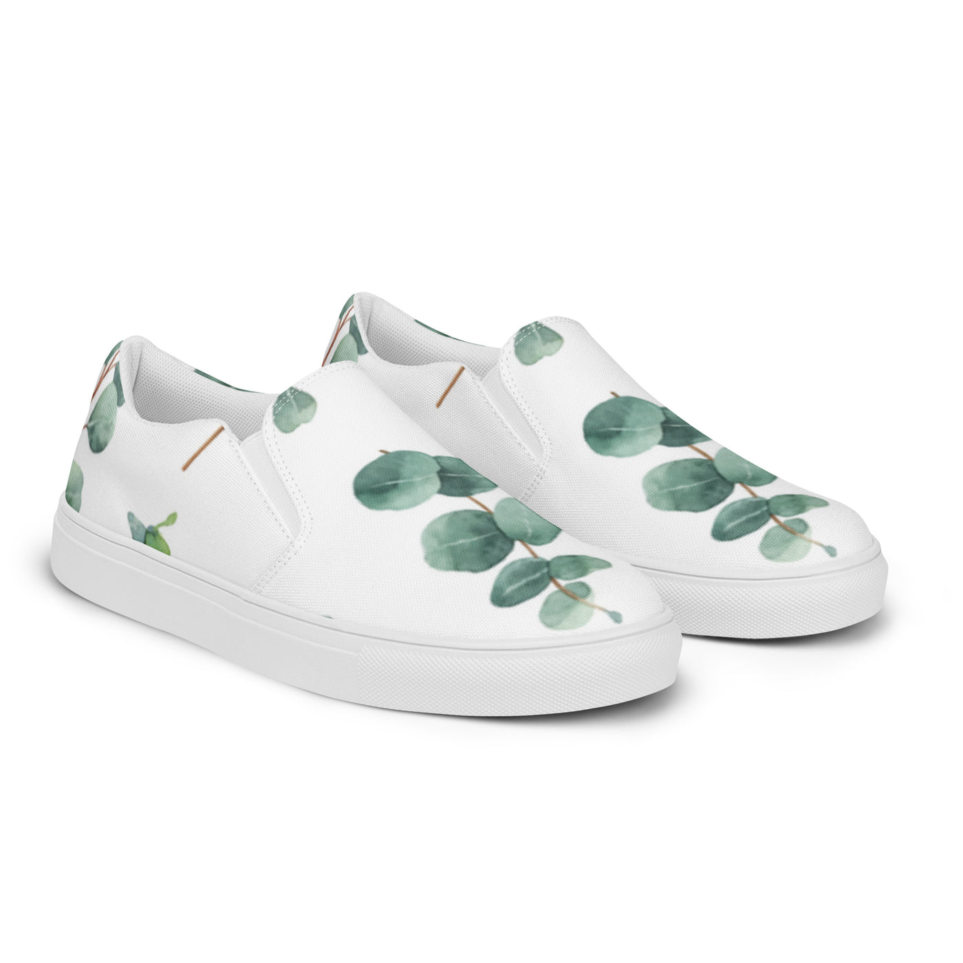 White slip-on canvas shoes with a eucalyptus leaf pattern in green tones, featuring Cachy’s Urban branding on the insoles