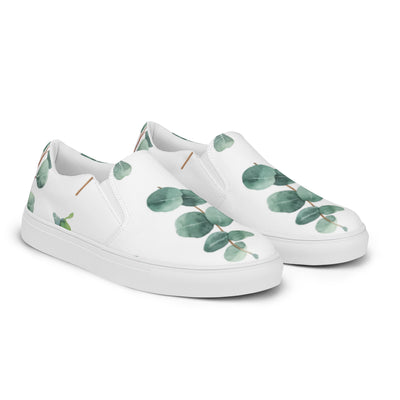 White slip-on canvas shoes with a eucalyptus leaf pattern in green tones, featuring Cachy’s Urban branding on the insoles