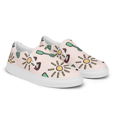 Pink slip-on canvas shoes with playful summer icons featuring suns, sunglasses, and shovels in a cartoon style